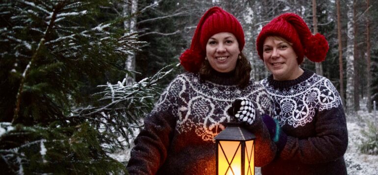 Two persons in the forest with Christmas hats and candle lantern.