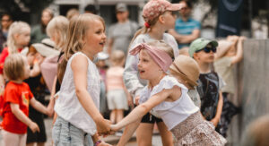 Kaksi lasta tanssivat iloisesti pitäen toisiaan käsistä kiinni.