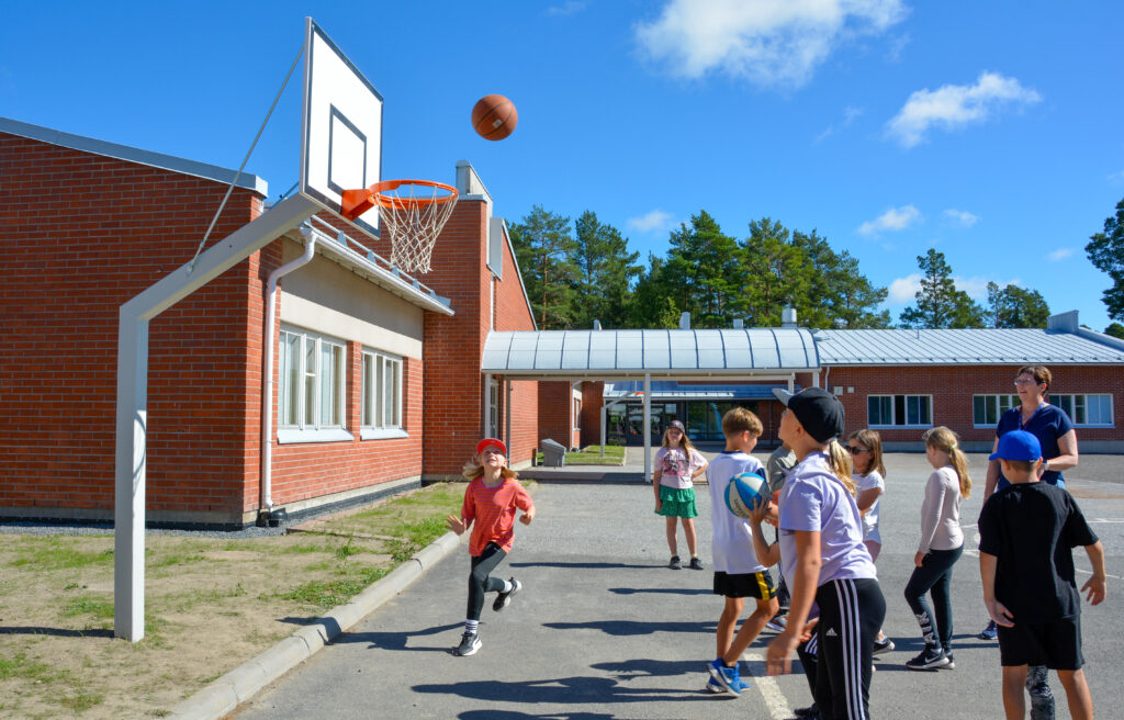 Koululaiset pelaamassa koripalloa.
