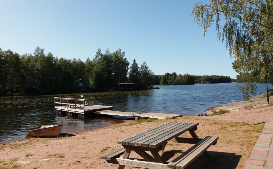 Beach Kaljasjärvi. A boat, a table with seats and a pier in the picture.