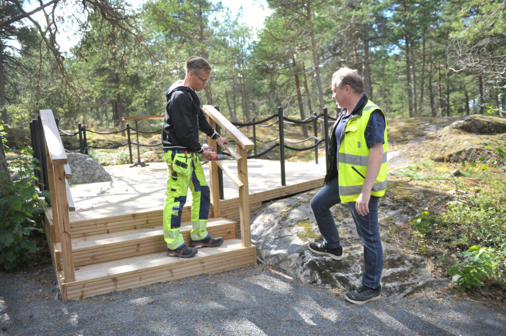 Kirvesmies Jan-Erik Hautakangas (vas.) nauttii siitä, että jokainen työpäivä on erilainen. Mukana kesäteatterilla oli rakennusmestari Riku Ollikainen.