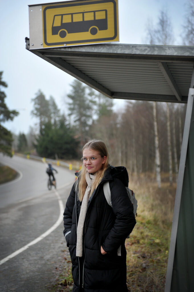 Kuvassa Inari Mäenpää odottamassa bussia bussipysäkillä.