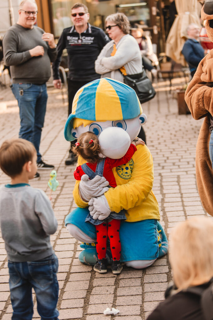 Palloiirojen maskotti halaa lasta. 