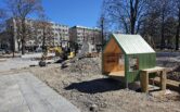Keskuspuiston rakennustyömaalla asennetaan leikkivälineitä. Kuvassa pieni mökki.