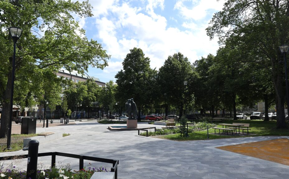 Photo of the renovated Rauma Central Park, featuring the Tasala Vilkk and Hakkri Iiro sculpture, newly paved walkways, and green trees.