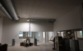 Papinpellon nuorisotilan ja nuorten työpajan alakerran tiloja rakennusvaiheessa. Kuvassa näkyy työvälineitä, valmiita seinärakenteita, suuria ikkunoita sekä rakennuksen pohjaratkaisua ja tilojen jakautumista.